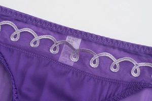 Macro d'une culotte en maille violette avec broderie ondulée et étiquette de lavage