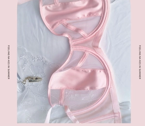 Detailed macro view of pink satin and sheer mesh fabric stitching on a French style bra