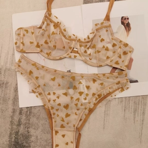 Flat lay of sheer lace lingerie set featuring yellow heart prints and ruffled trim details