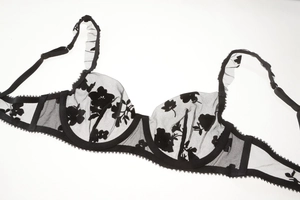 Detail of sheer black lace bra featuring delicate floral embroidery and ruffled straps