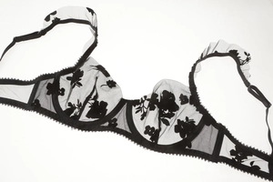 Detail of black sheer mesh bra featuring floral embroidery and ruffled strap design