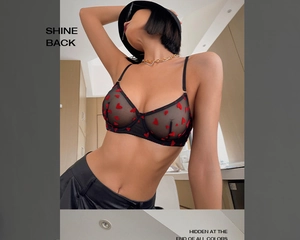 Détail d'un soutien-gorge en maille noire avec motifs cœurs rouges et fines bretelles