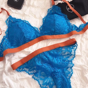 Detail of dark blue lace lingerie set with contrast orange straps and eyelash trim edges