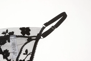 Detailed macro view of black sheer lace lingerie with floral embroidery and adjustable straps