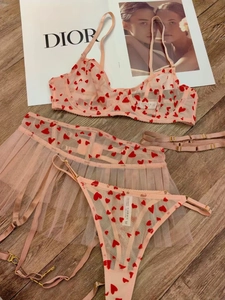 Détail à plat d'un ensemble de lingerie en maille rose avec cœurs rouges et boucles en métal