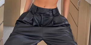 Détail du pantalon en similicuir noir à taille haute avec plis rétro et fini mat