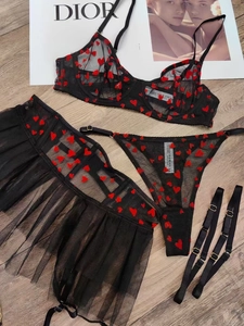Détail à plat d'un ensemble de lingerie en résille à cœurs noirs avec jarretière et soutien-gorge