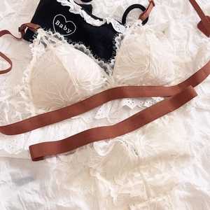 Detail of white floral lace lingerie set with contrasting brown satin straps on fabric