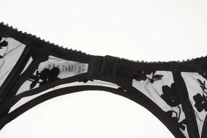 Detail of black floral lace embroidery and sheer mesh on the back of the bra strap