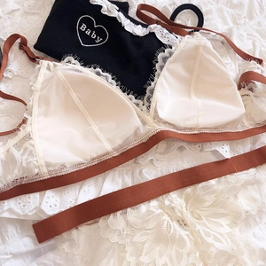Detail of white lace triangle cup bra with brown straps and heart baby embroidery