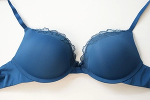 Detail of petrol blue push-up bra with delicate lace trim and central bow decoration