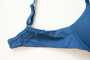 Detail of navy blue lace bra showing adjustable strap and seamless wing texture