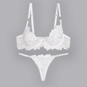 Detail of white lace bra set featuring leaf embroidery and gold metallic accents