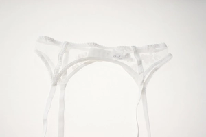 Detailed view of white floral lace garter belt with sheer mesh and scalloped edges