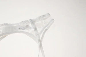 Detail shot of white semi-transparent floral lace embroidery on sheer mesh fabric lingerie