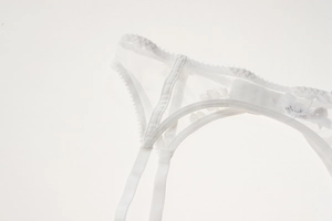 Detail of white floral lace garter belt featuring sheer mesh fabric and scalloped edges