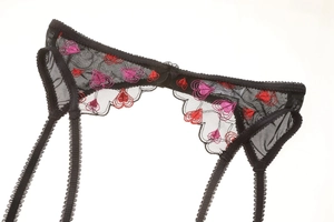 Close-up of black mesh garter belt with floral embroidery and adjustable straps
