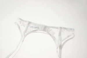 Close-up of white floral embroidery lace garter belt with adjustable straps and back hooks