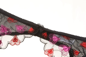 Close-up of heart embroidery on black lace with a delicate mesh bow detail
