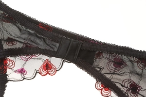 Detail of red heart embroidery on sheer black lace with adjustable double hook closure