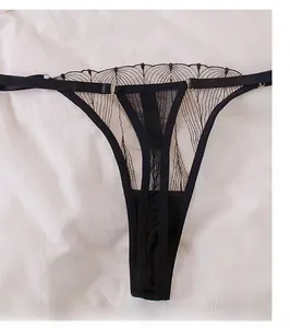 Detail view of black lace thong with sheer mesh texture and thin straps on white background