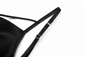 Gros plan d'une bretelle de lingerie noire avec boucle de réglage en métal doré