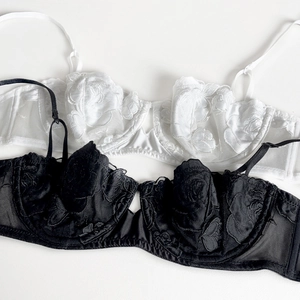 Detail of rose embroidery on black and white lace bras with adjustable thin straps