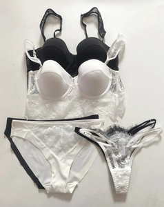 Flat lay detail showing black and white lace lingerie sets with eyelash trim and satin fabric