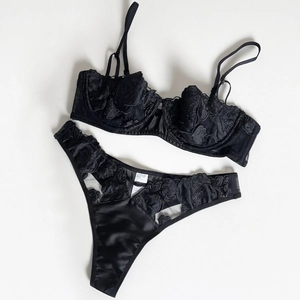 Detailed macro view of black lace bra with rose embroidery and satin fabric texture