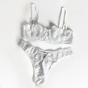 Close-up of white lace lingerie set with detailed rose embroidery and mesh fabric texture