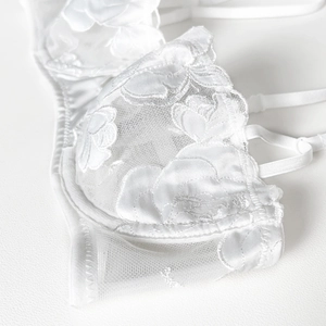 Detail showing white lace bra with exquisite 3D floral embroidery and mesh fabric texture
