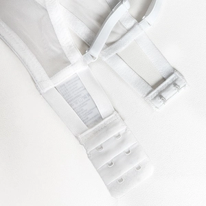 Detail view of white lace bra featuring three-row hook-and-eye closure and mesh fabric
