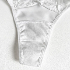 Detail view of white lace panty with cotton lining and high-quality floral embroidery
