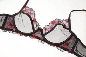 Gros plan d'un soutien-gorge en maille noire avec broderie détaillée de cœurs rouges et roses