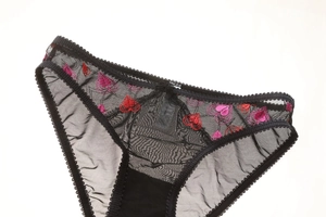 Détail d'une culotte en dentelle noire transparente avec broderies de cœurs roses