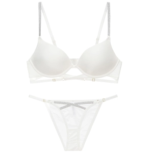 Detail view of white lingerie set featuring shiny fabric and rhinestone cross straps