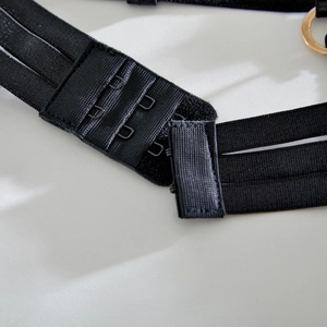Detail of black elastic strap with three-row back hooks and gold metal ring fastener