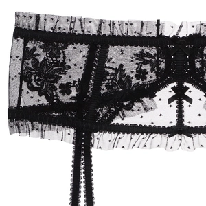 Dettaglio della giarrettiera in pizzo nero con trama a pois e fiocchi decorativi
