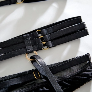 Detail of sexy black lingerie showing golden O-rings and multi-strap mesh texture