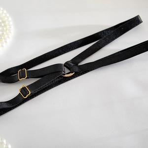 Close-up of black satin elastic straps with gold metal buckles and luxury pearl accents