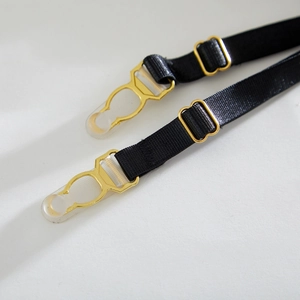 Detail of black elastic lingerie straps with gold metal adjusters and clear hooks