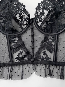 Close-up of black lace bustier featuring floral embroidery and mesh dot details