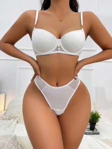 Detail of white lace bra set featuring gold chain straps and elegant pearl accents