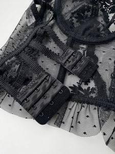 Close-up of black lace bra back with three-row hook-and-eye closure and mesh detail