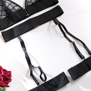 Flat lay of black mesh lace lingerie set with suspender belt and a romantic red rose