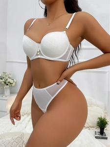 Close-up of white quilted lace bra with pearl detail and sheer mesh panel thong set