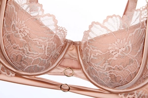Detailed close-up of lotus pink lace bra with silver embroidery and gold ring accents