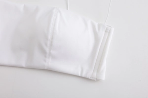 Detail of white seamless bra showing fine vertical stitching and elastic shoulder strap