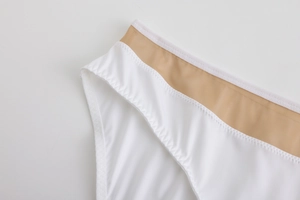 Detailed close-up of seamless white fabric with khaki mesh waist and zigzag stitching