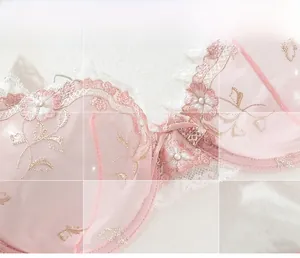 Close-up of pink floral embroidery lace with pearl bead detail and soft mesh fabric